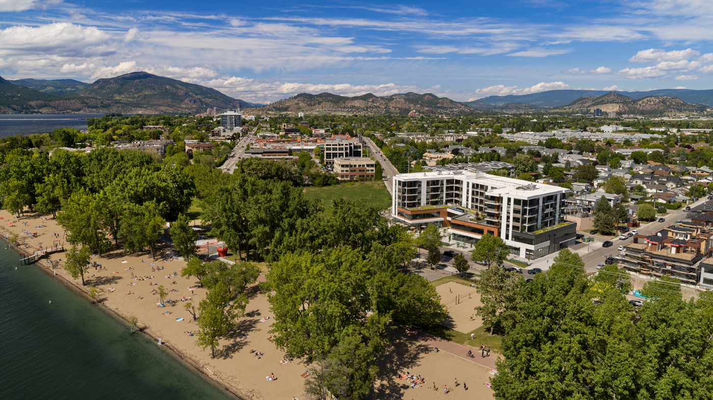 an exterior, birds-eye view of The Shore Kelowna, with the lower mission neighbourhood surrounding and Gyro Beach in the foreground