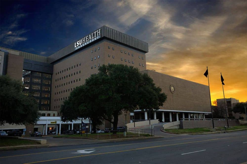 A view of Louisiana State University Shreveport School of Medicine's campus, featuring a modern building with green lawns and trees in the foreground.