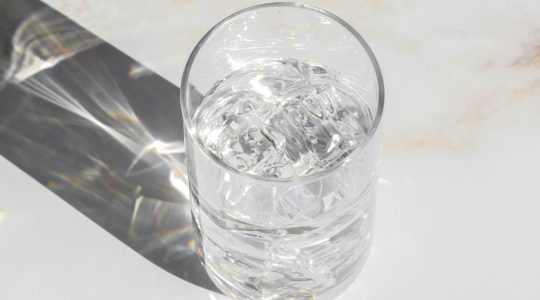 Verre d'eau avec de la glace sur un comptoir de marbre.