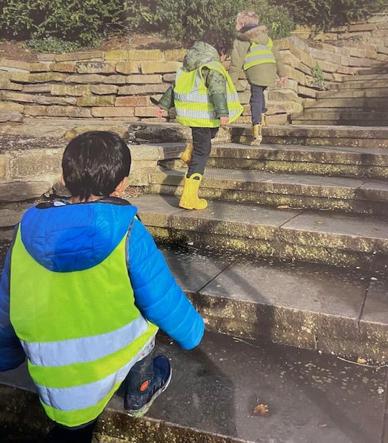 A group of children in yellow vests walking up stairs

Description automatically generated