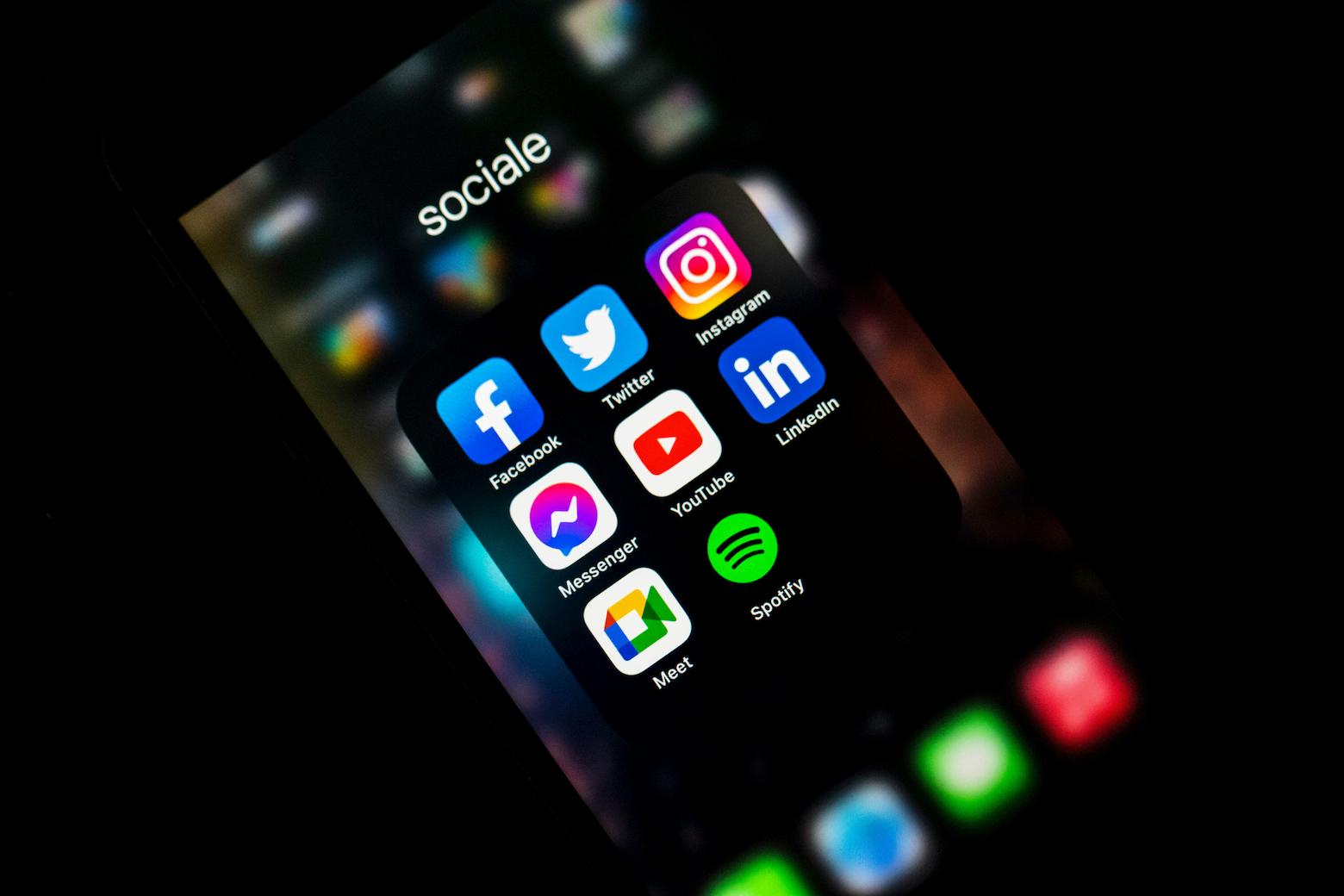 A phone's screen showing social media apps installed on it, such as facebook, twitter, instagram, linkedin, and more.