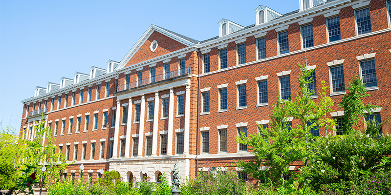 A view of the exterior of the main building of Georgetown University School of Medicine, featuring brick walls, large windows, and a green lawn in the foreground.