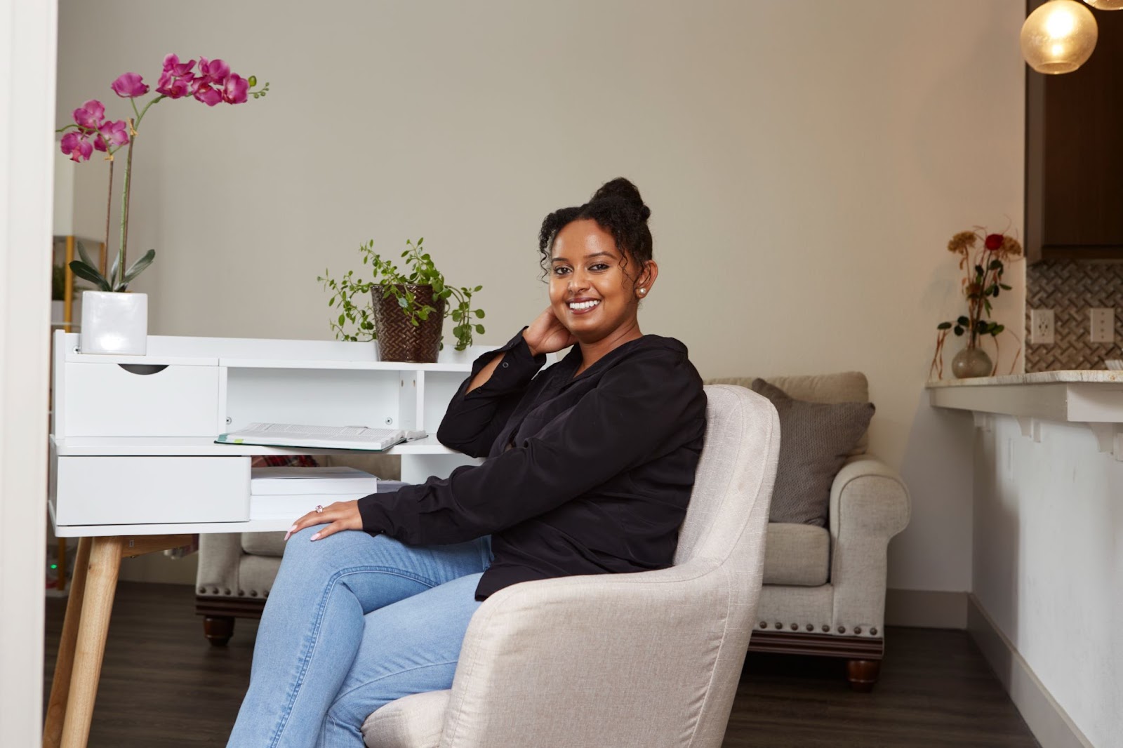 Woman in a black shirt sitting in a chair and smiling. 