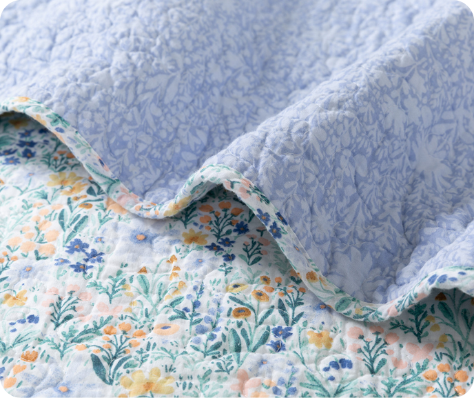 A close up shot of our floral Camellia Cotton Quilt Set with its blue reverse side showing.