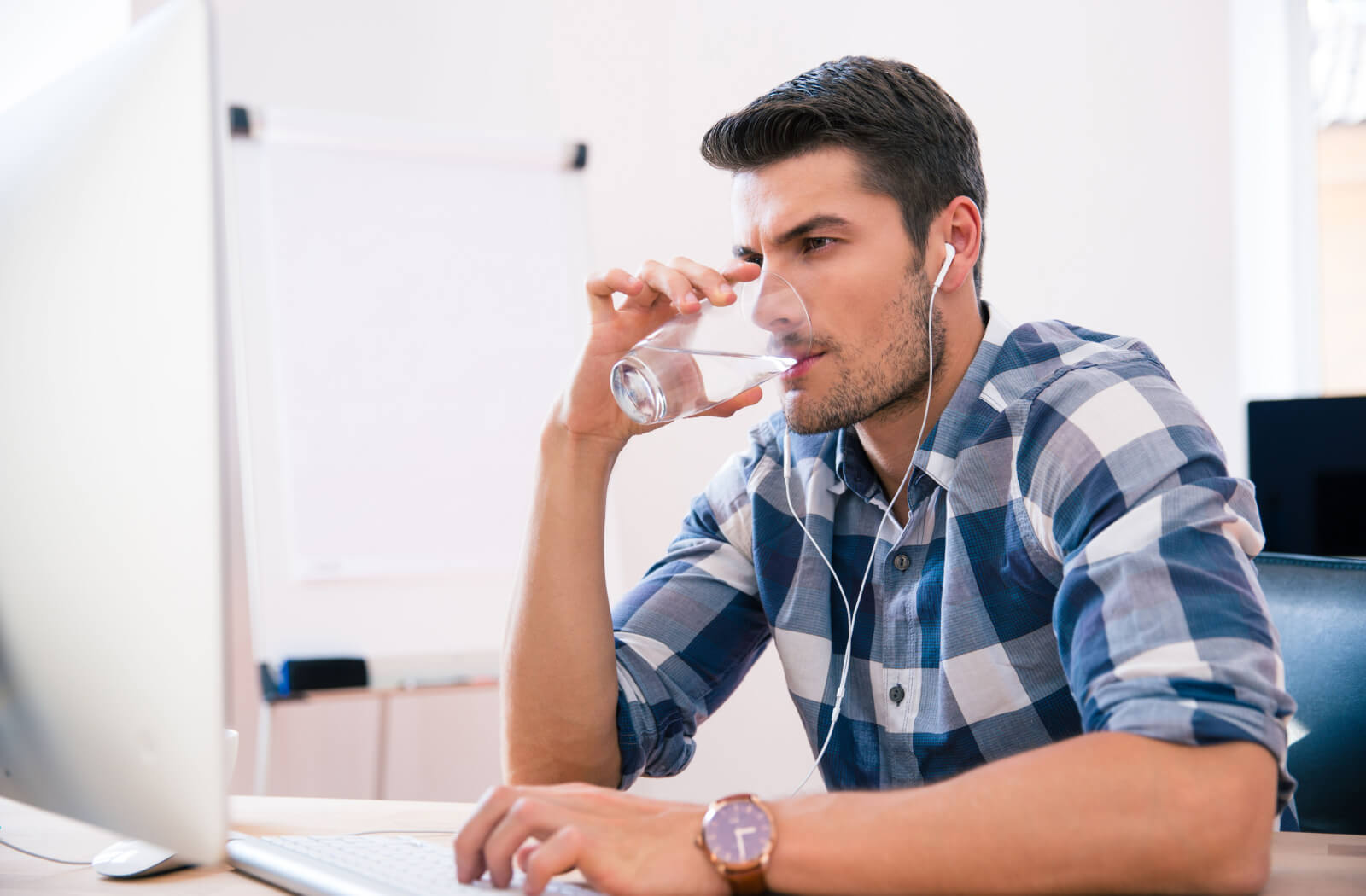 A man drinking a glass of water while working.
