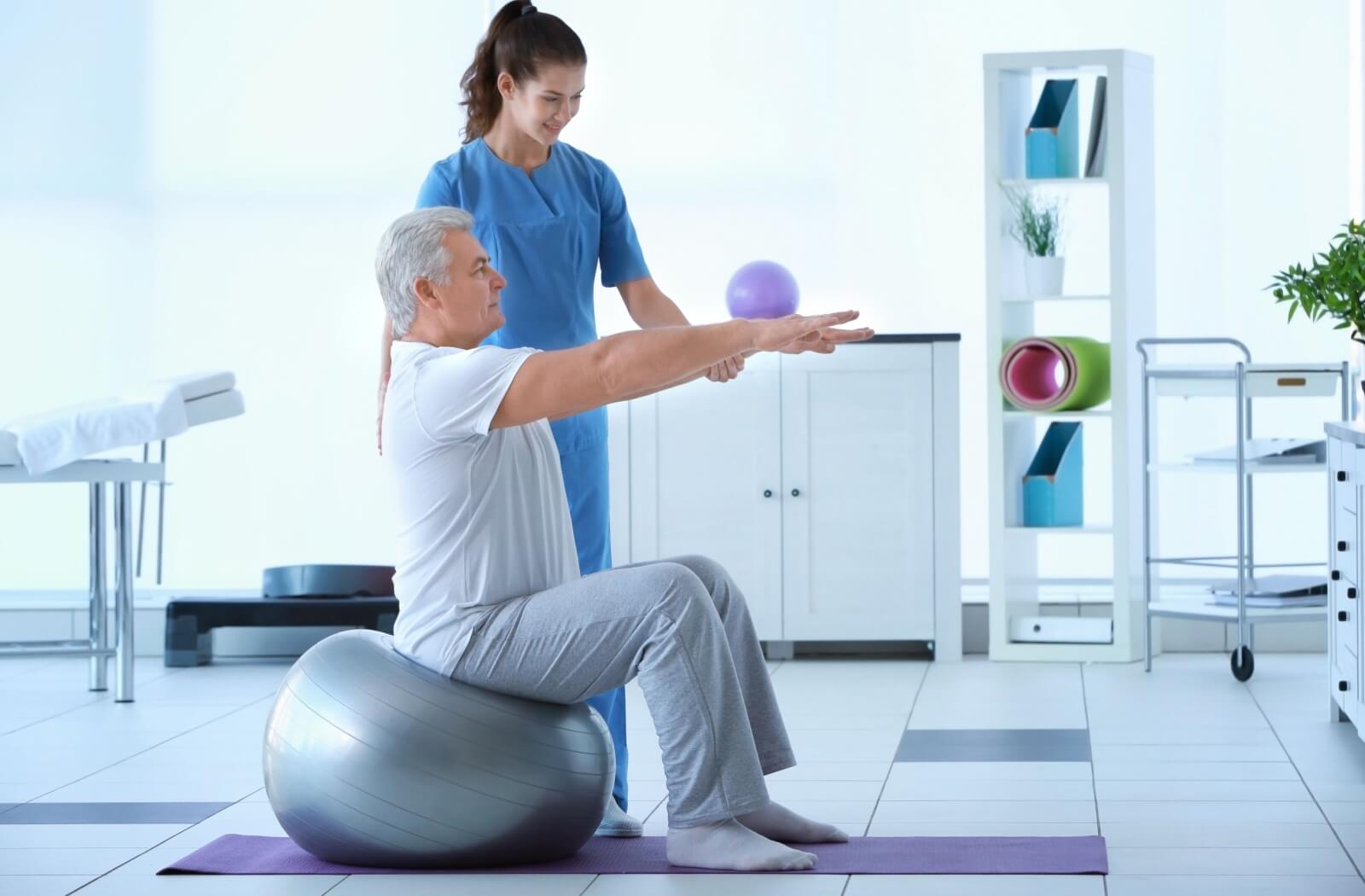 An older adult man exercising with the assistance of a physical therapist.