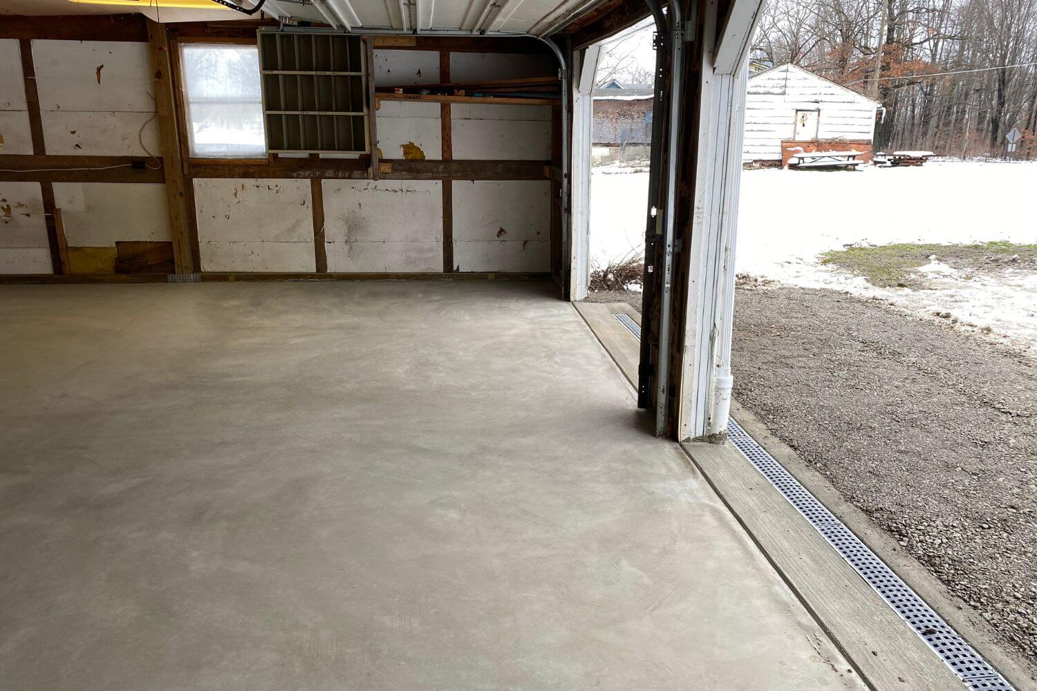 new concrete floor in a residential garage, with new exterior french drainage installed to assist with water drainage issues