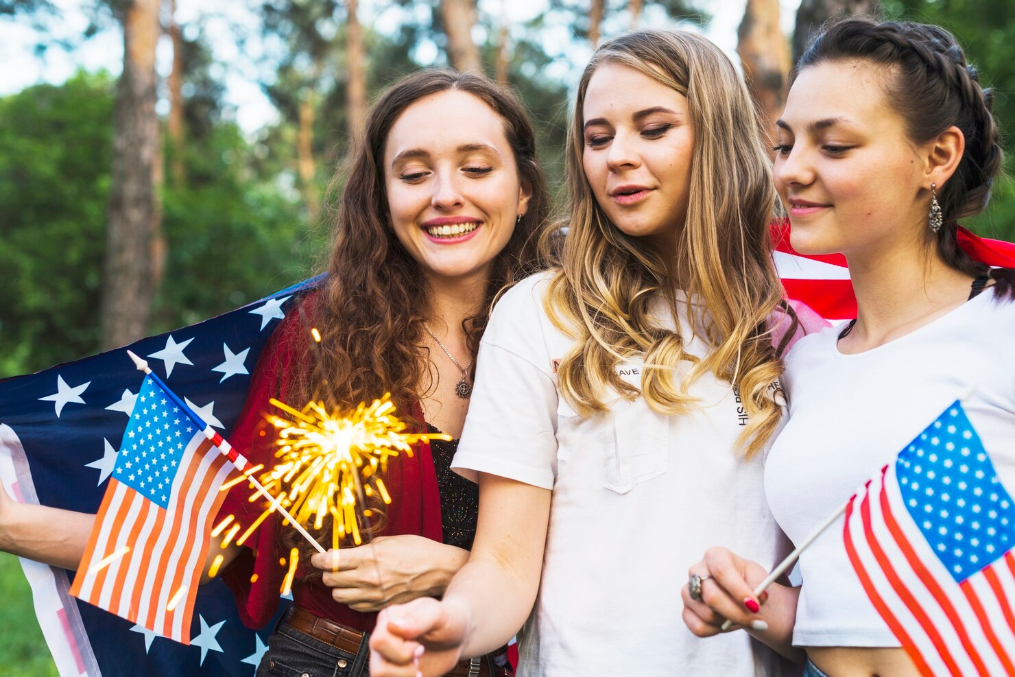 Girls celebrating 4th of July with flags and sparklers.