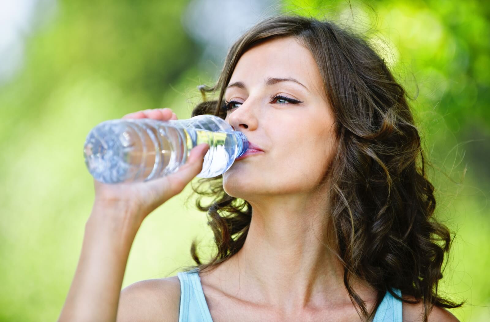 A woman drinking water from a plastic bottle.