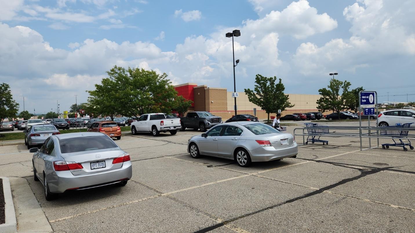 A parking lot with cars and a shopping cart

Description automatically generated