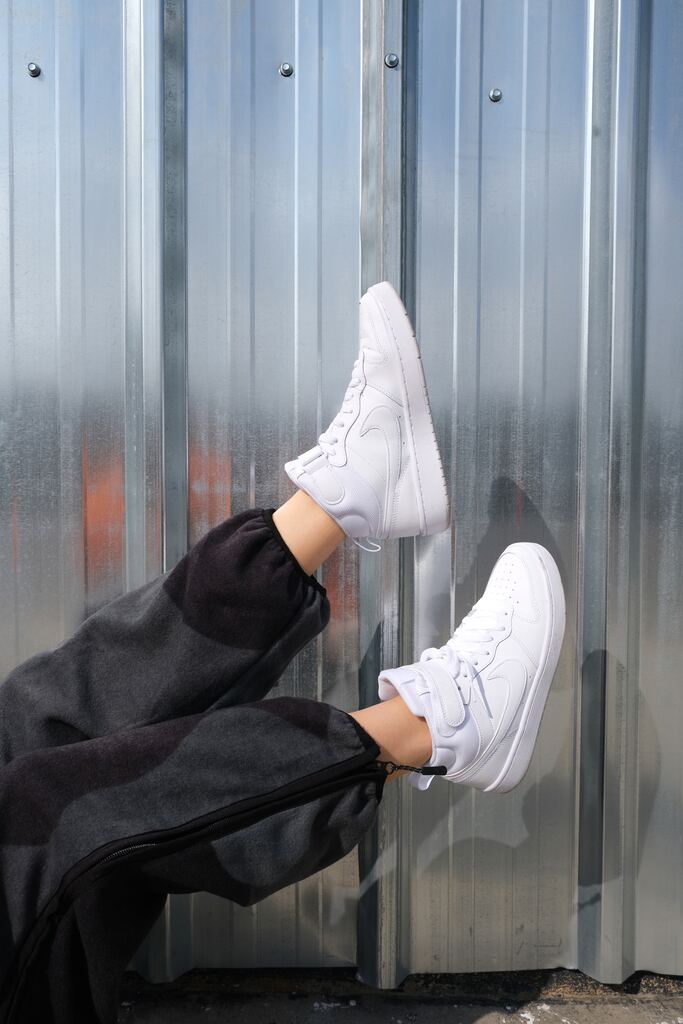 Woman's legs in black joggers and white sneakers