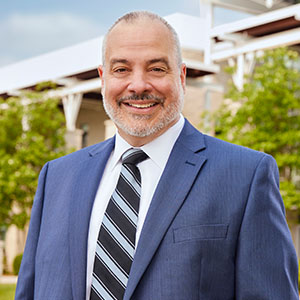 Photo headshot of Dr. Joe Bertolino, smiling dressed in a suit and tie. 