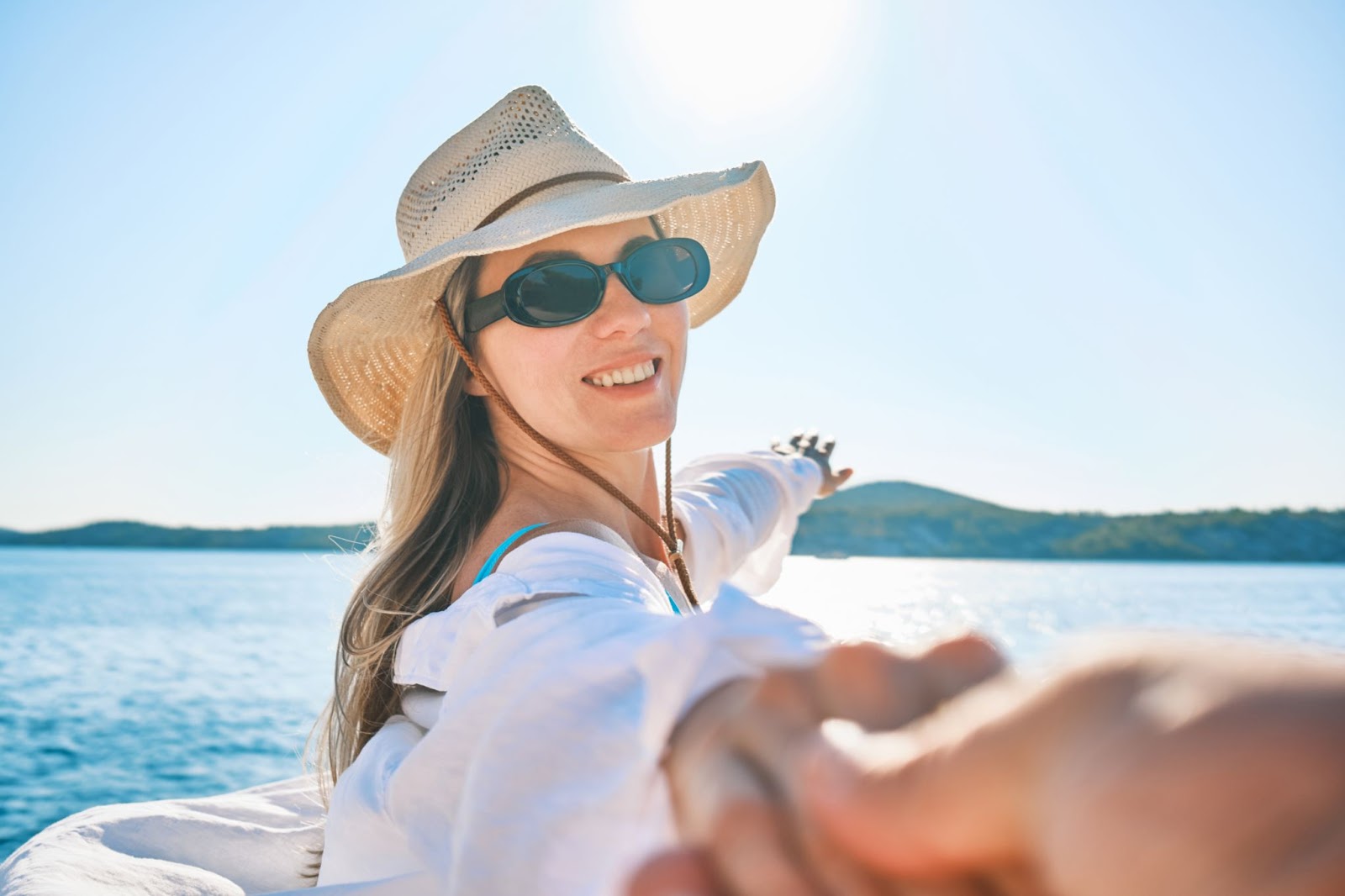 A woman wearing sunglasses and a wide-brim hat protecting her face and eyes from the sun.
