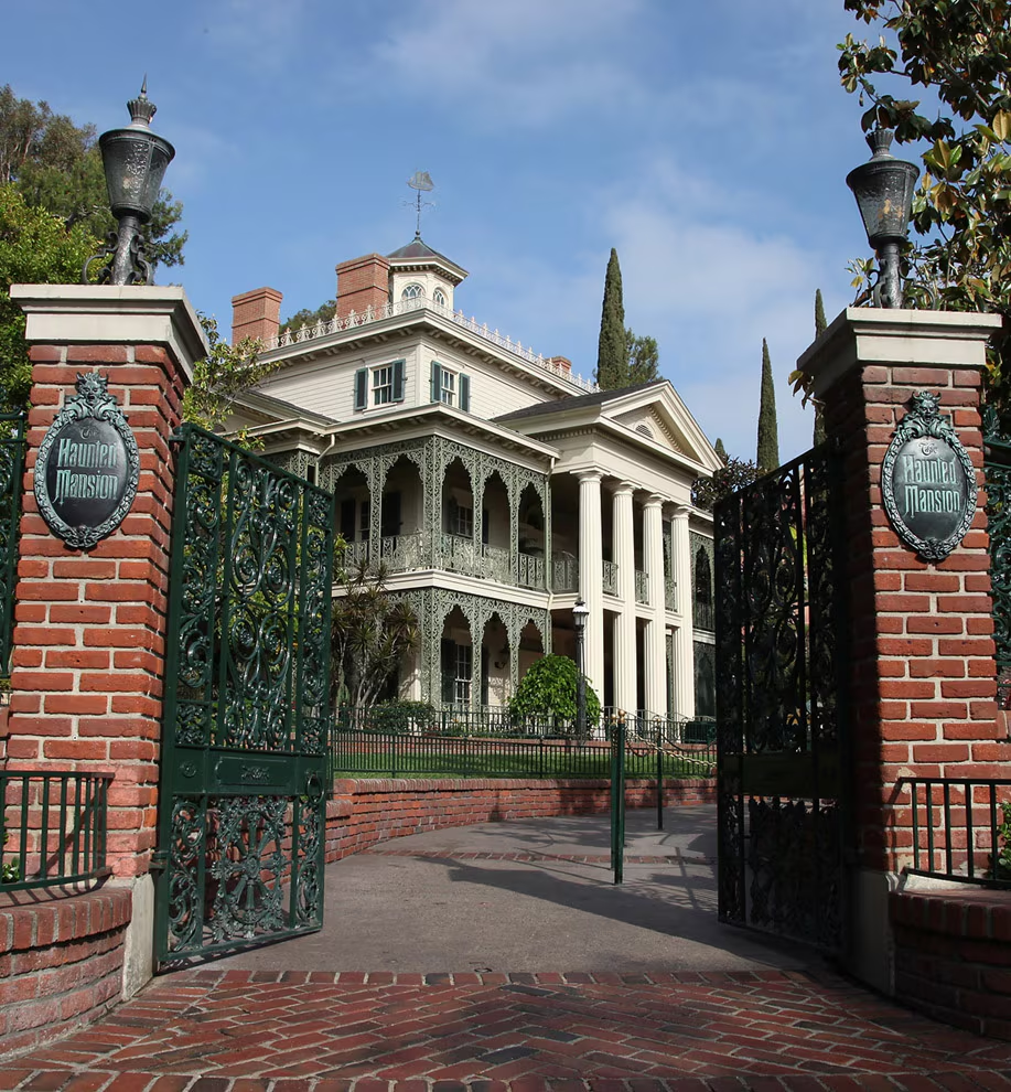 A view of the outside of Disneyland's Haunted Mansion, through the front gates of the ride