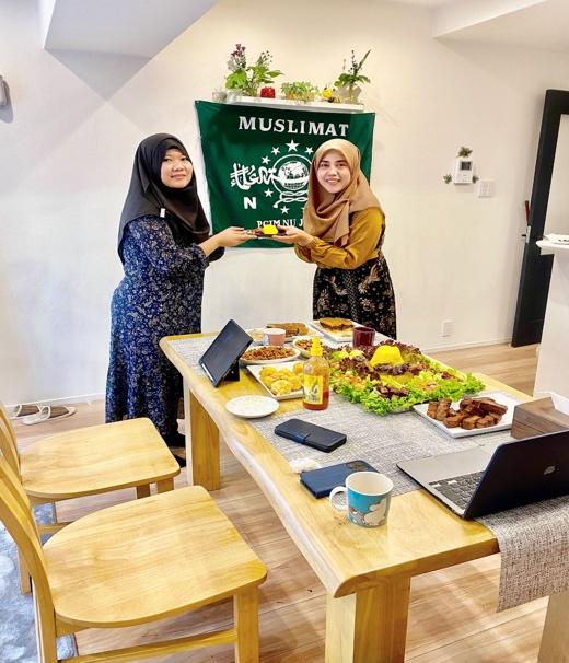 Two women holding a green sign

Description automatically generated