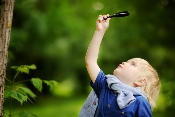 boy with magnifying glass outside; nature scavenger hunt for toddlers