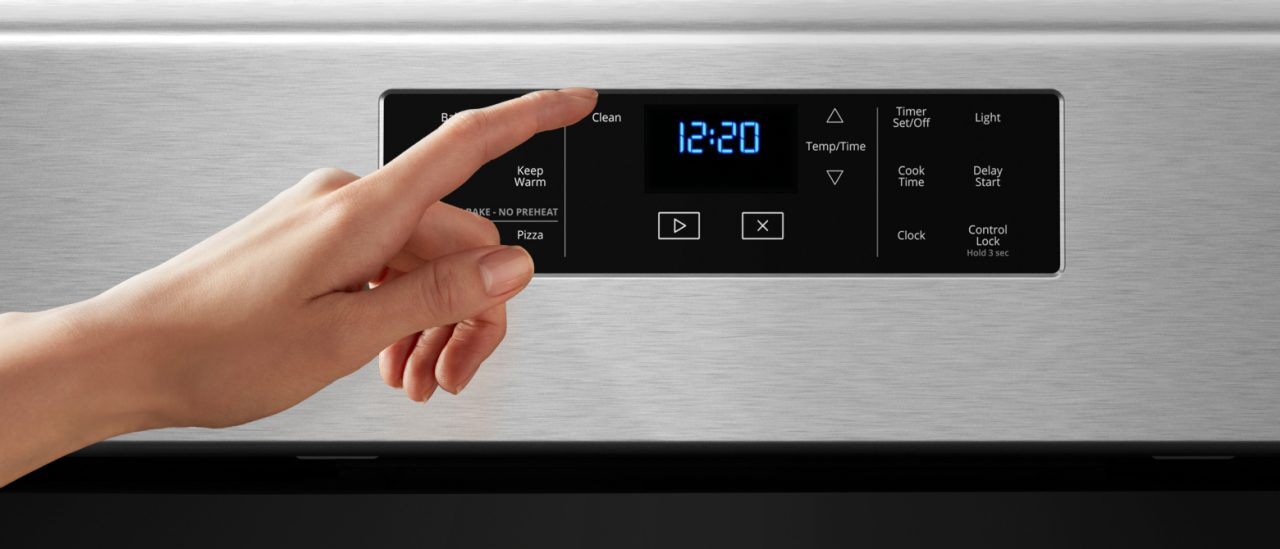 Hand pressing the self-cleaning option on oven control panel