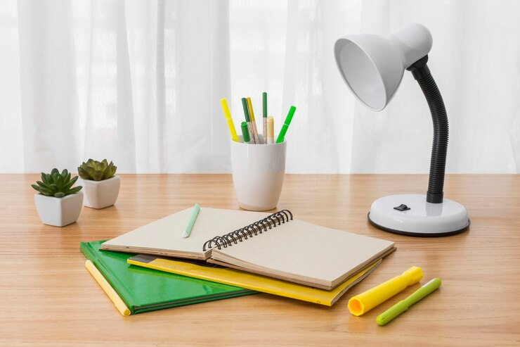 Desk with notebook, lamp casting light on study area.