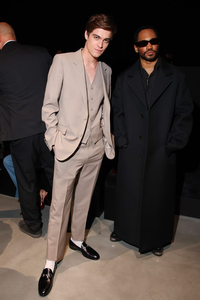 Picture showing two celebs at the Milan Fashion Week Men’s FW24, one dressed in a stylish all black look and the other in a suit
