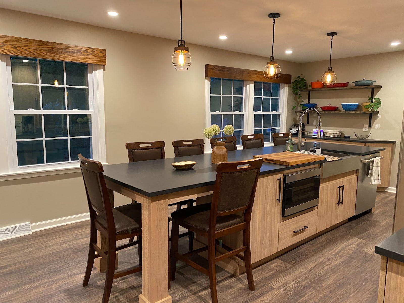 An island area in the kitchen of the home. The island has wooden cabinets underneath and black countertops.