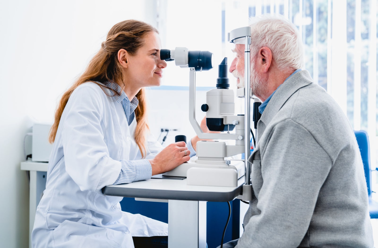 An optometrist examines an older patient's eyes for diabetic eye diseases