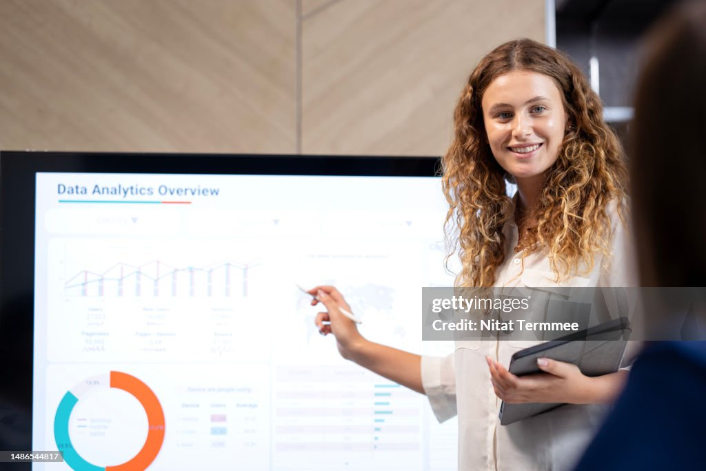 A person presenting a Data Analytics Overview on a screen, pointing at a graph with a pen