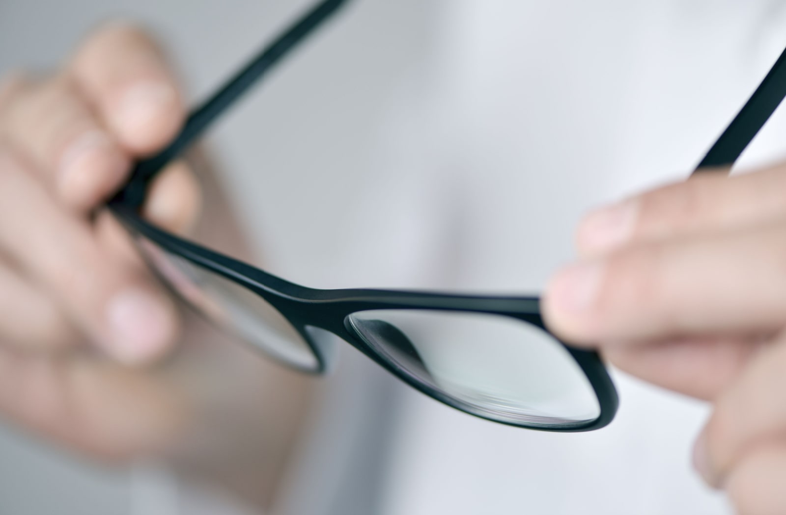 Someone holding onto a pair of glasses with progressive lenses
