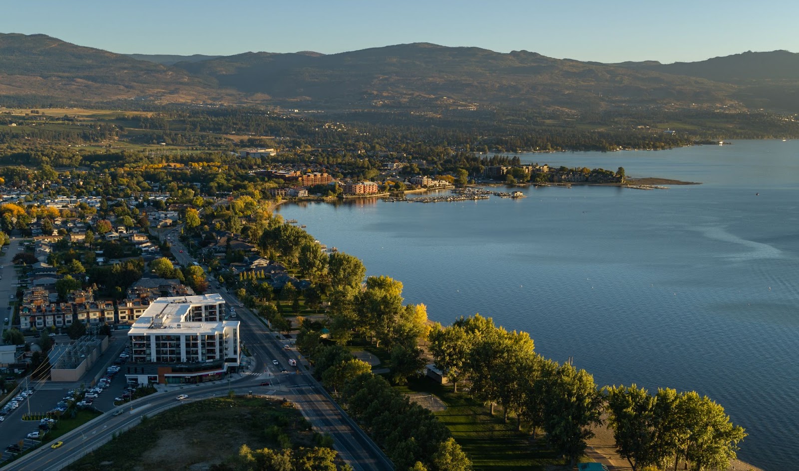 a birds-eye view of The Shore Kelowna, with the Okanagan Lake and mountains in the background