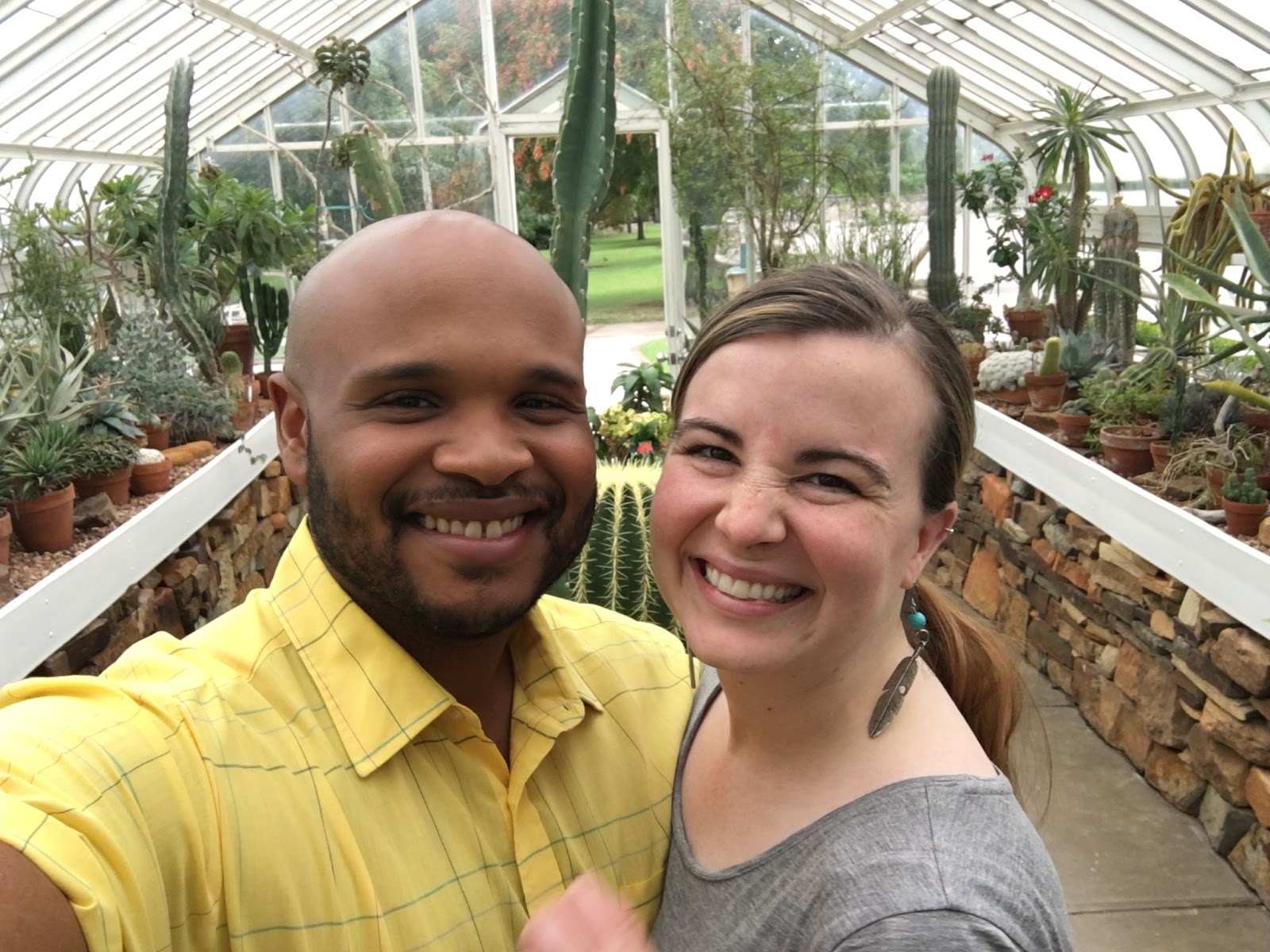 John and wife posing for a photo inside a cacti greenhouse.