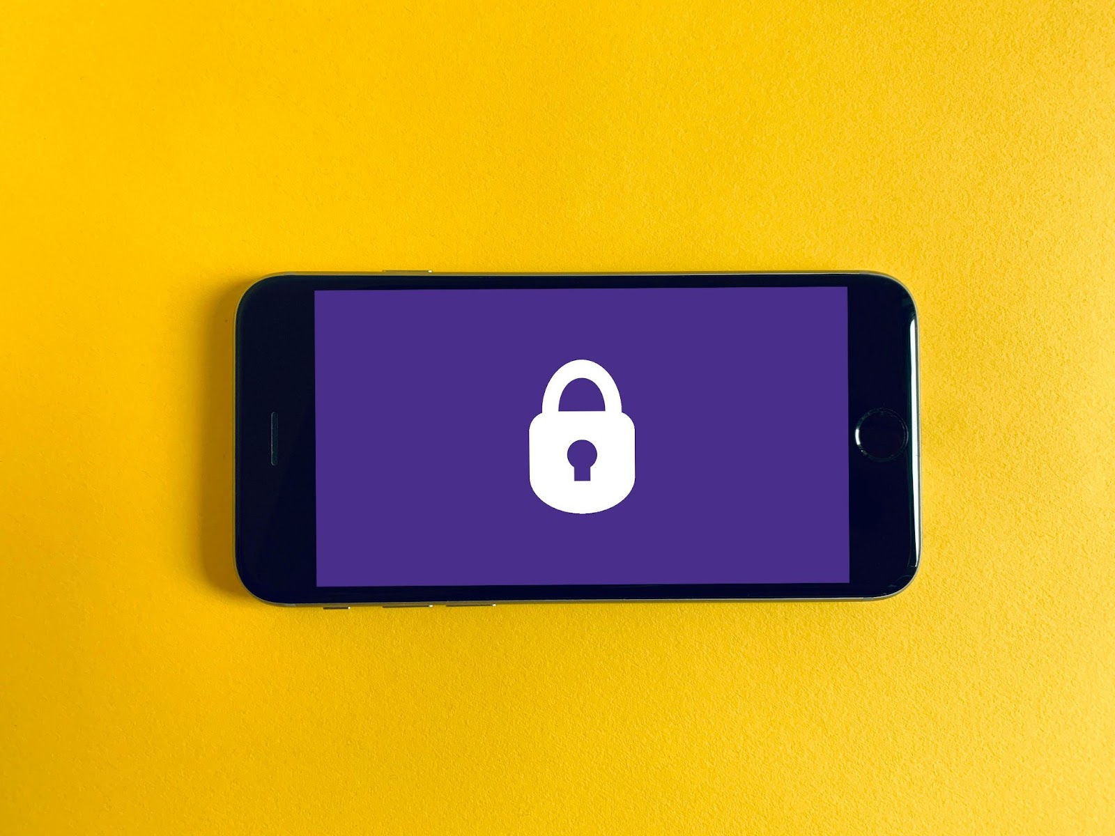 Smartphone on a yellow background displaying a safety lock icon, symbolizing protection against data theft