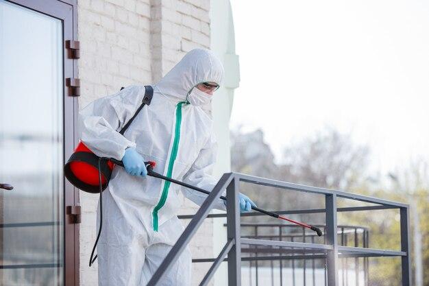 Coronavirus Pandemic. A disinfectant in a protective suit and mask sprays disinfectants in the room.