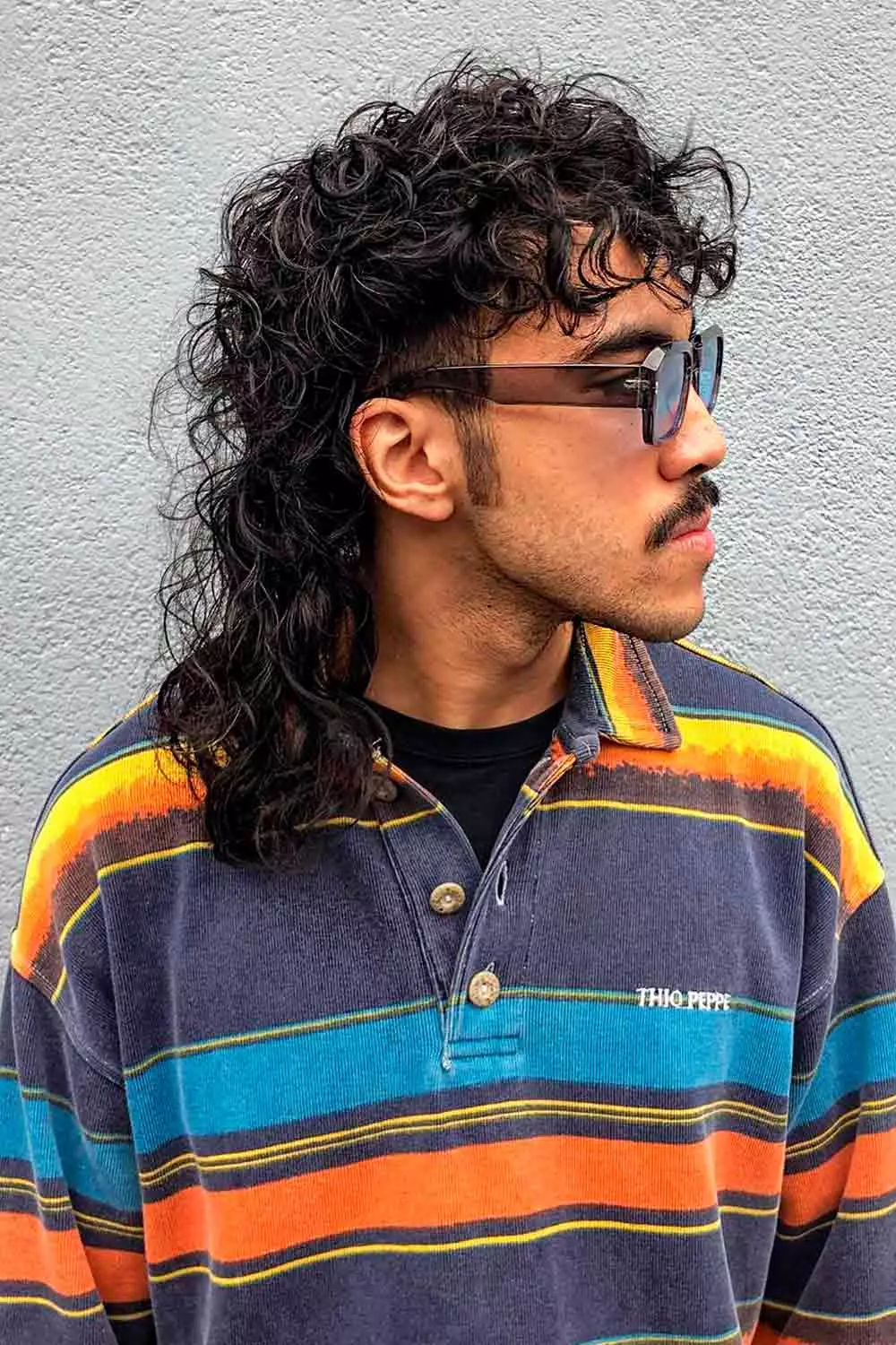 Side picture of a guy rocking the curly wolf cut  for men  with curls