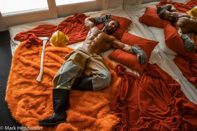 Bruce Jones in a photography shot by Mark Henderson lying on orange fun fur dressed as a naked sexy firefighter