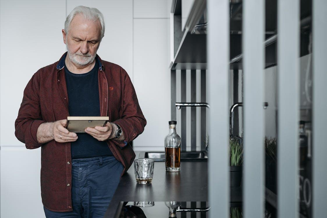 Free A Man with Gray Hair Holding a Picture Frame Stock Photo