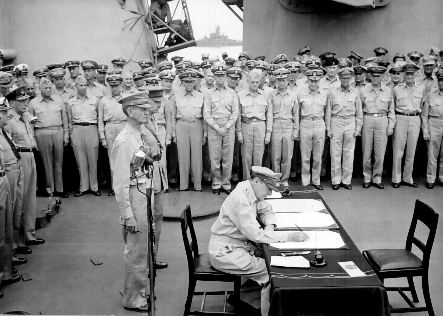 General Douglas MacArthur signs as Supreme Allied Commander during formal surrender ceremonies on the USS Missouri in Tokyo Bay.