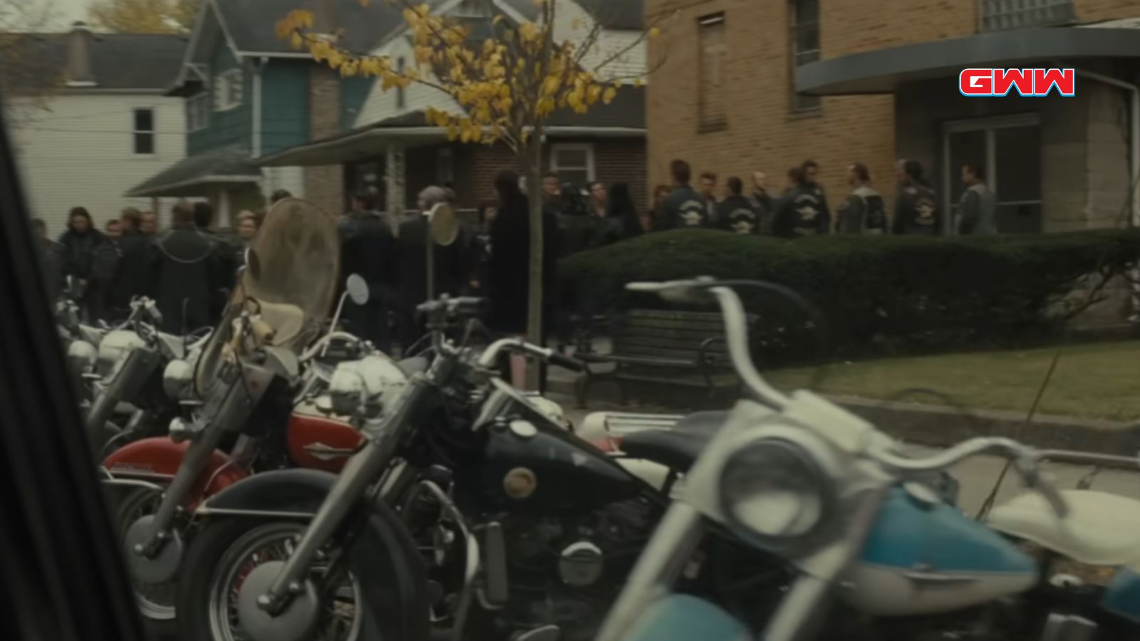Group of motorcyclists gathering outside a house, several bikes parked.