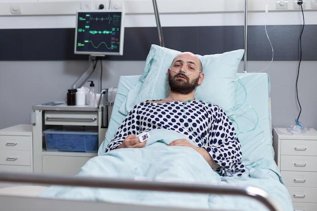 Free photo patient lying in hospital bed with respiratory problems connected to monitor measuring vitals in private ward. middle aged man with illness and low oxygen saturation waiting for clinical consult.