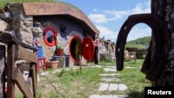 Marija Milicevic opens a door to a hobbit house named "Ober", in the Bosnian Hobbiton village, Rakova Noga, Bosnia and Herzegovina, May 9, 2023.