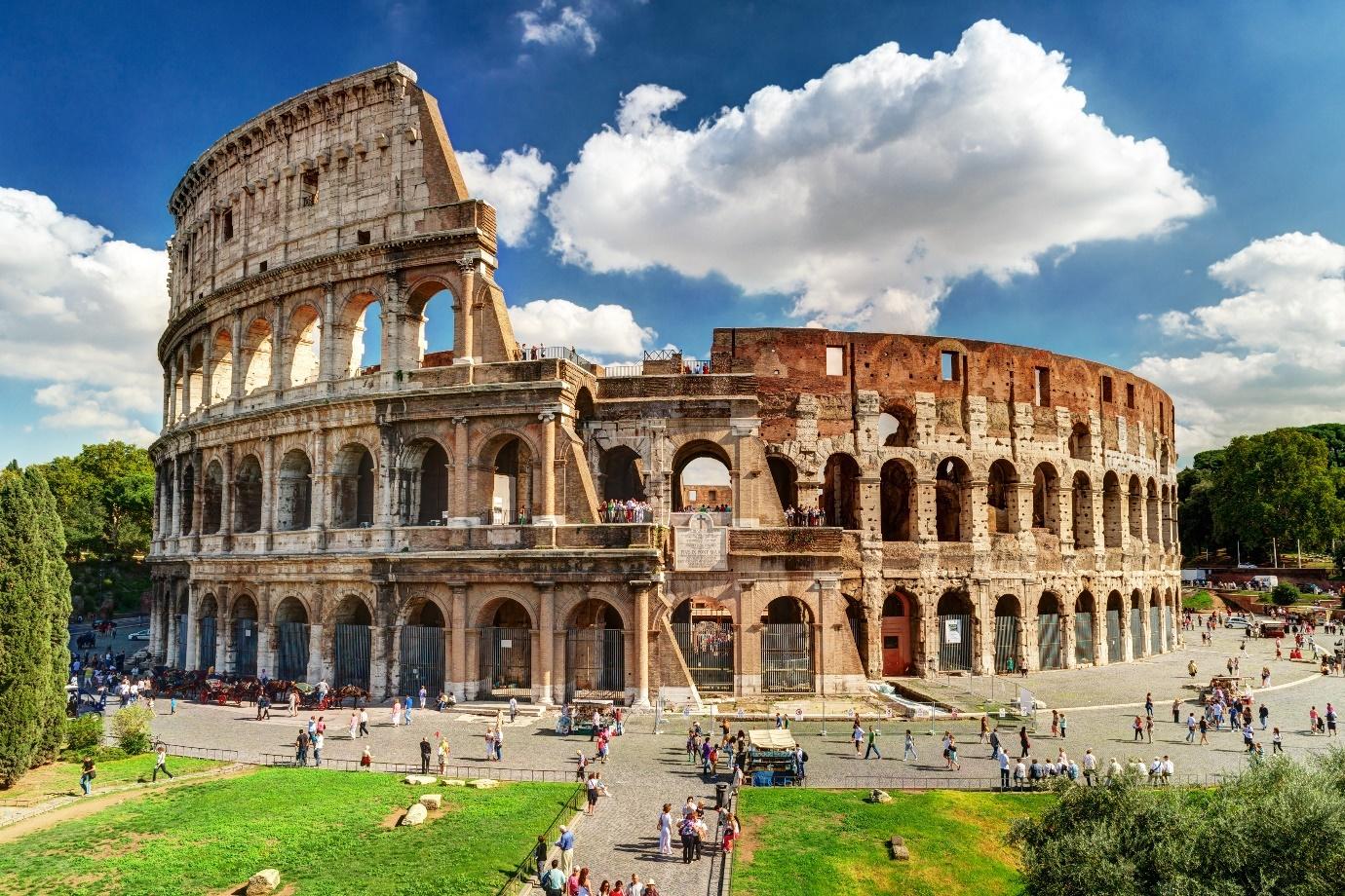 A large circular stone building with arches and arches with Colosseum in the backgroundDescription automatically generated