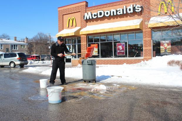 A person cleaning a trash can in front of a mcdonald's restaurant

Description automatically generated