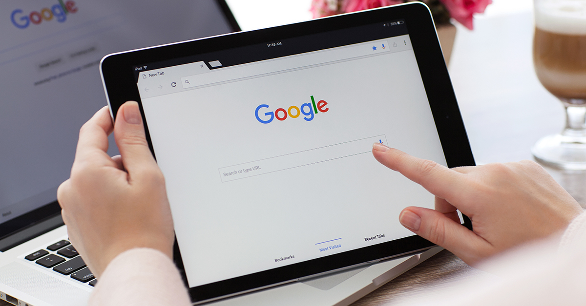 A person's finger is pointing at the google logo on a tablet while checking their online reputation.