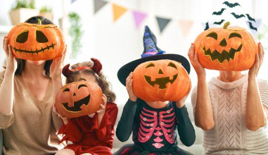 Family holding decorate pumpkins over their faces