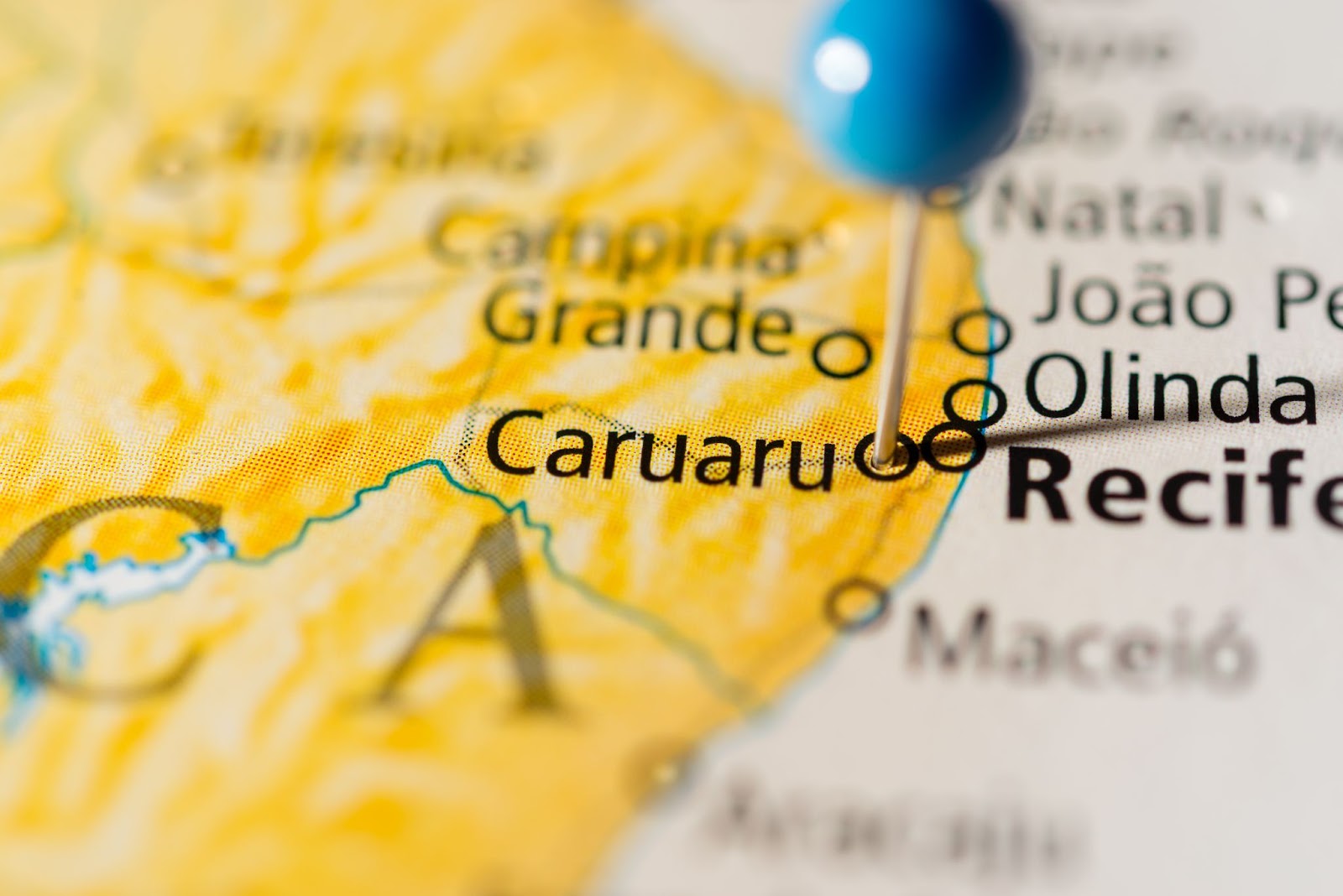 Alfinete azul marcando a localização de Caruaru em um mapa colorido do Brasil.