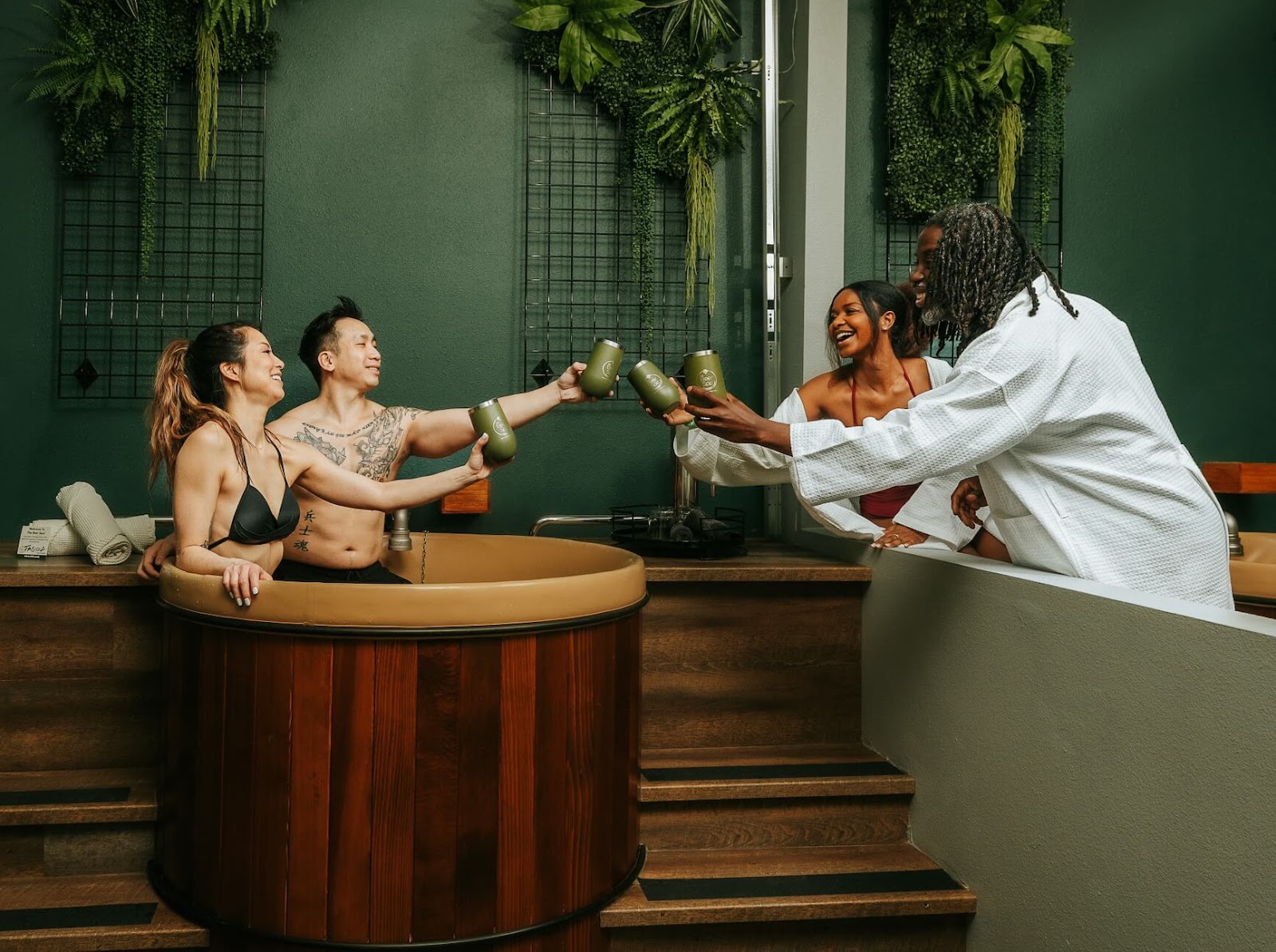 Two couples saying cheers with tumblers and taking a beer bath at Oakwell Beer Spa