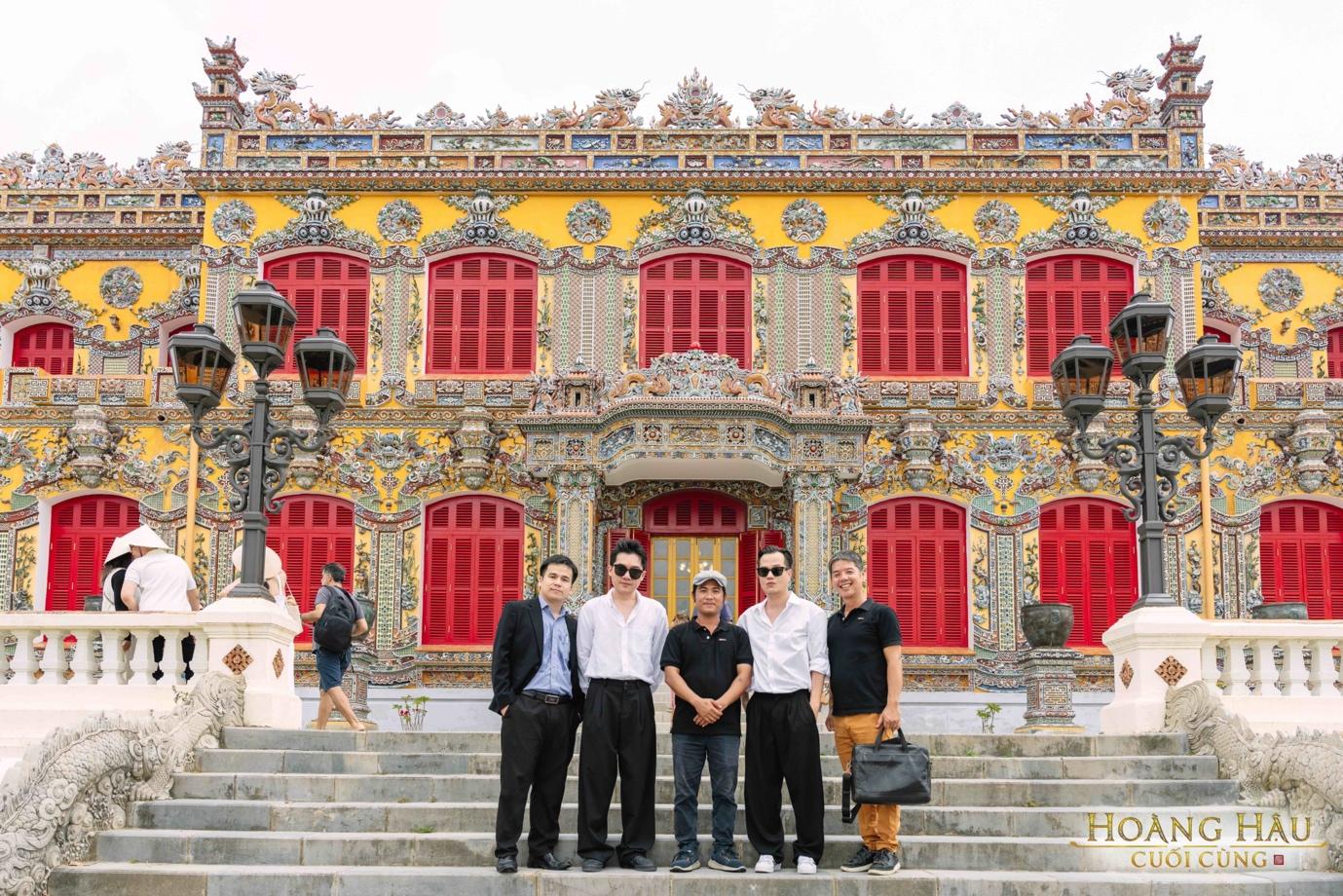 A group of men standing on stairs in front of a colorful building

Description automatically generated