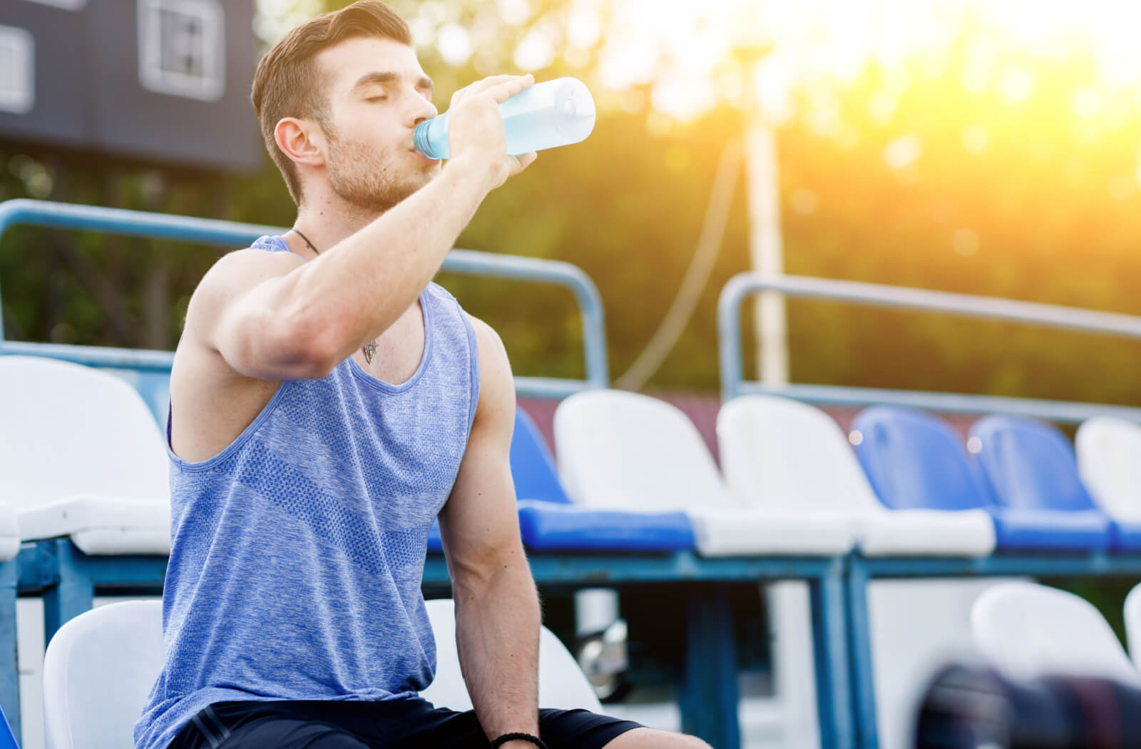 A man drinking water from a plastic bottle after working out.