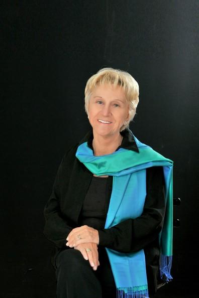 A person with short blonde hair wearing a blue and black robe

Description automatically generated