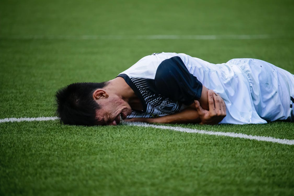 an athlete on a soccer field suffering from an overuse injury