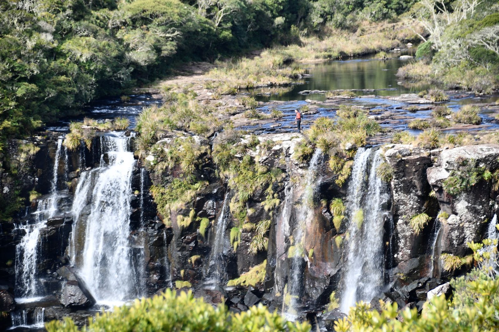 Cachoeira no Parque Nacional de Aparados da Serra. A queda d’água é formada por pedras escuras e está rodeada pela Mata Atlântica