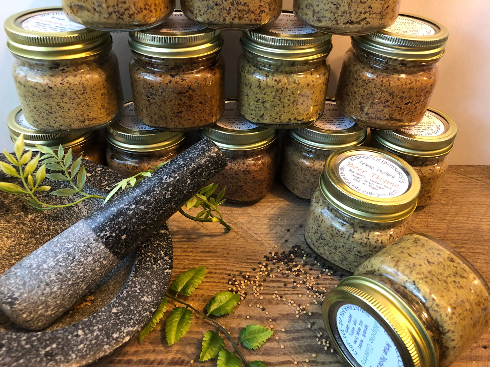 several jars of artisanal mustard with mortar and pestle in the foreground